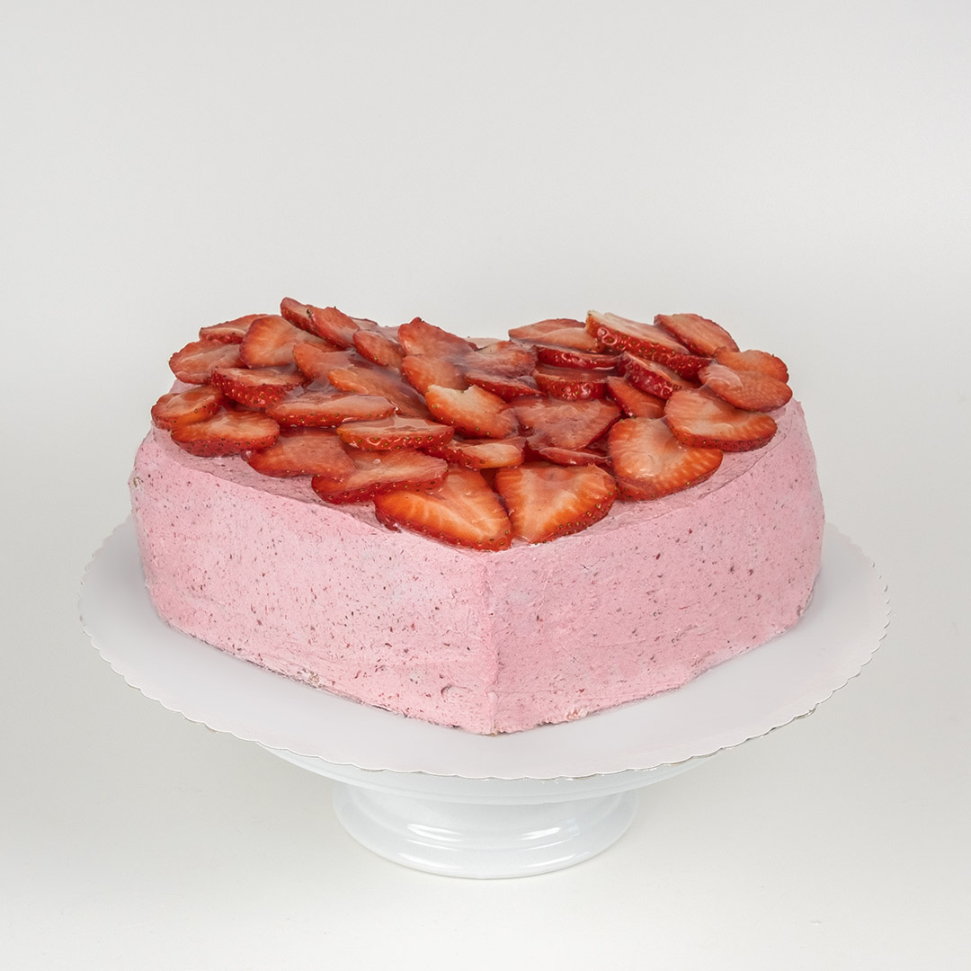 Herzförmige Torte mit Vanilleboden, Erdbeersahne und frischen Erdbeeren auf einem weißen Teller