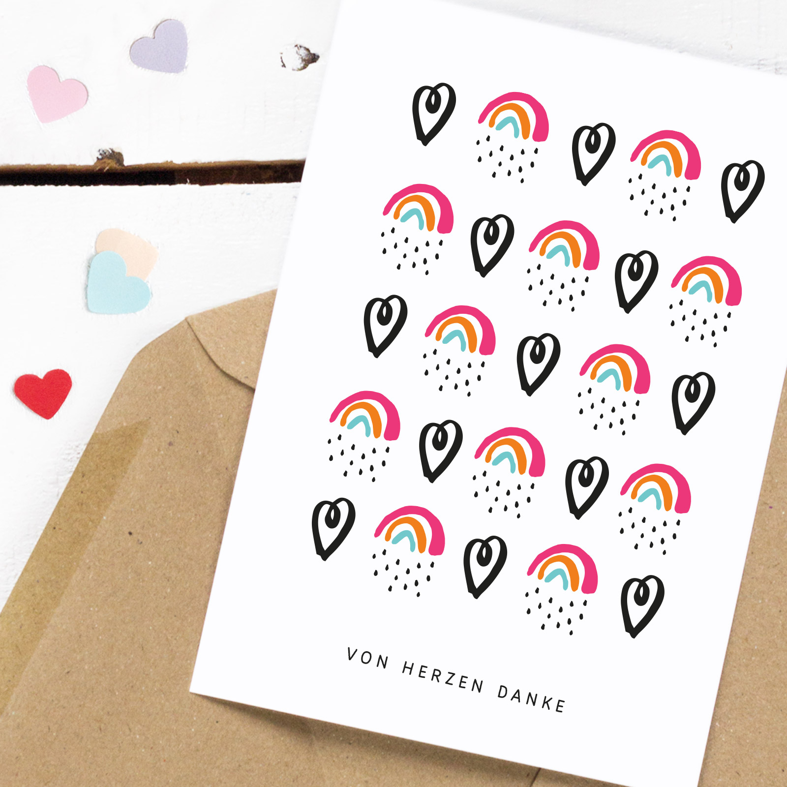 Postkarte mit abwechselndem Muster aus schwarzen Herzen und Regenbogen, darunter der Spruch "Von Herzen Danke"